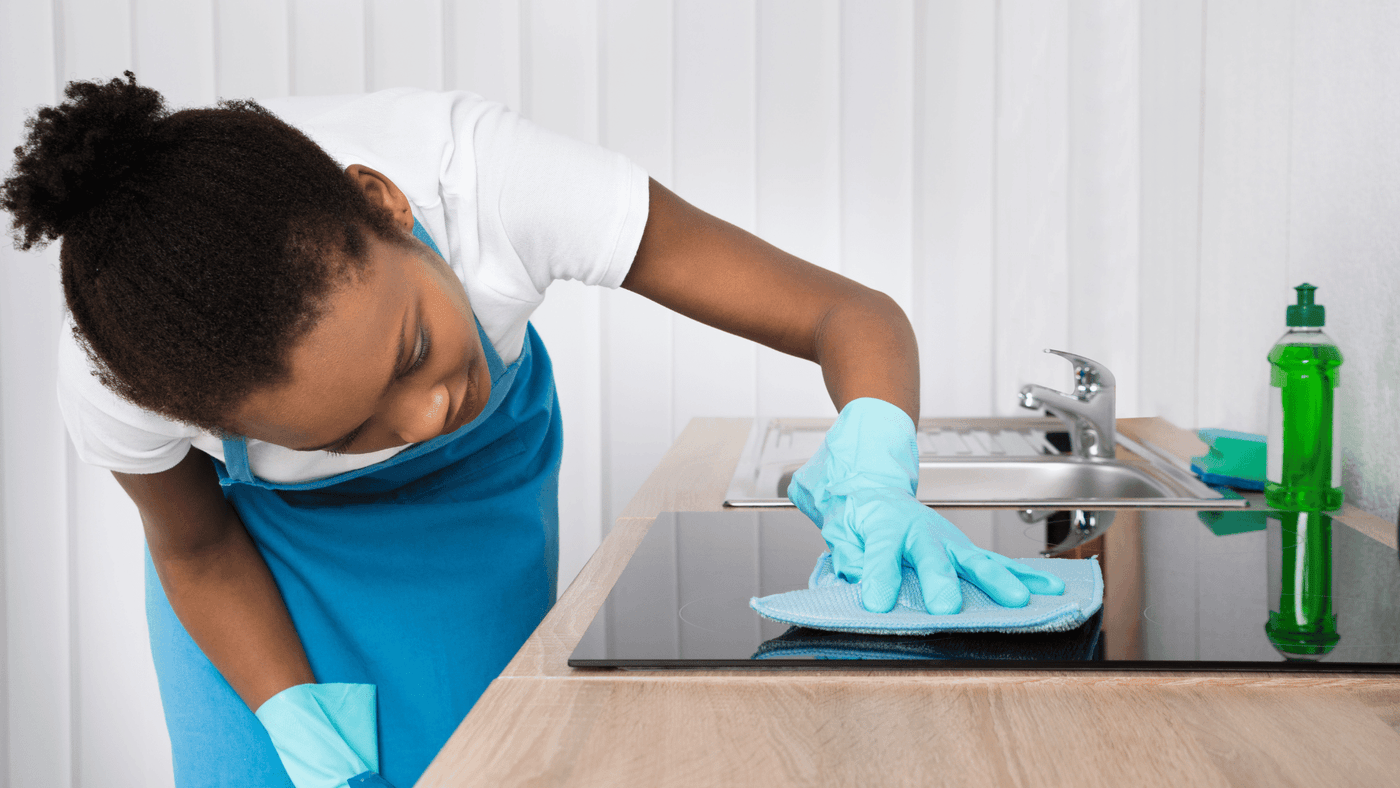 Cleaner wiping lower cabinets during a home cleaning visit
