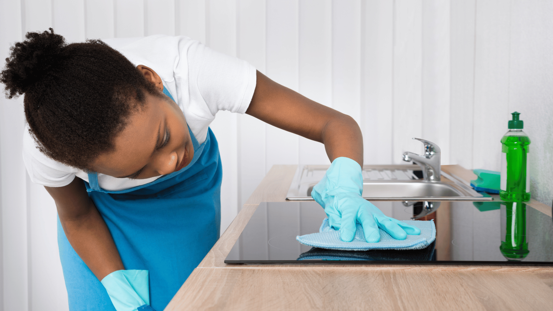 Cleaner wiping lower cabinets during a home cleaning visit