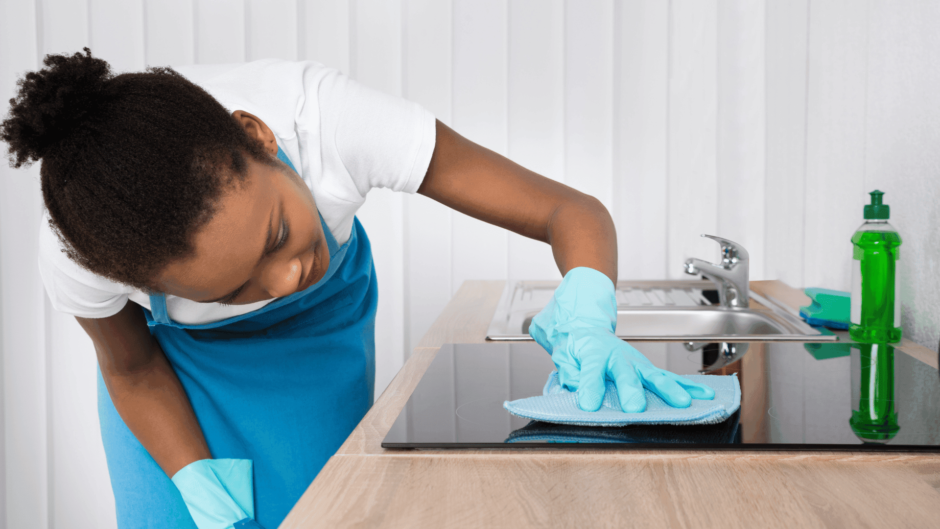 Cleaner wiping lower cabinets during a home cleaning visit
